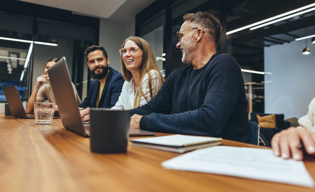 Successful group of businesspeople having a briefing in a boardroom. Happy businesspeople smiling while working together in a modern workplace. Diverse business colleagues